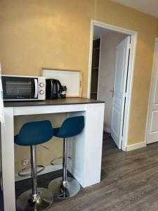 a kitchen with two stools at a counter with a microwave at Appartement cosy terrasse parking 20 mn Paris in Savigny-sur-Orge