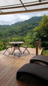 un patio con mesa y sillas en una terraza de madera en Cabina Brisa Escondida - Walking distance from river en Savegre