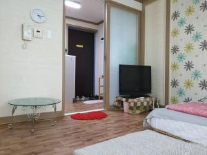 uma sala de estar com televisão e uma mesa num quarto em Cozy accomodation near chilgok gyeongdae hospital em Daegu