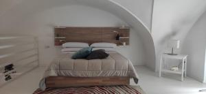 ein weißes Schlafzimmer mit einem Bett mit einem Kopfteil aus Holz in der Unterkunft CasaMas in Brindisi
