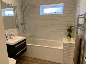 a white bathroom with a tub and a sink and a sink at Oakwood in Lymington