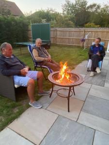 a group of men sitting around a fire in a yard at Oakwood in Lymington