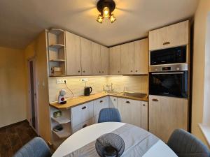 a kitchen with wooden cabinets and a table with chairs at Szilvás 10 in Szigliget