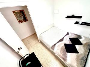 Habitación pequeña con cama y maleta en Las habitaciones de Svetlana, en Alicante