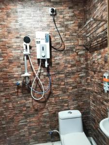 a bathroom with a toilet and a camera on a brick wall at Tang Hotel in Alor Setar