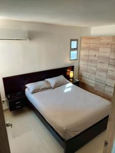 1 dormitorio con 1 cama grande y cabecero de madera en Apartamento amoblado NUEVO frente sede selección Colombia, en Barranquilla