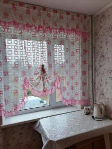 una ventana con cortinas rosas y blancas y una mesa en Квартира улица Абая 18 en Borovoye