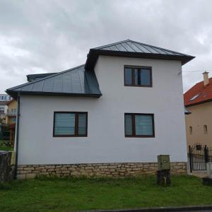 uma casa branca com um telhado preto em Dovolenkový dom eLAra em Smizany