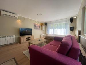 a living room with a purple couch and a tv at Hubane saunaga kodumajutus Tartu linna südames in Tartu
