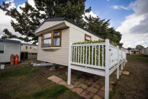 a small white tiny house with a white railing at 6 Berth Caravan With Decking Nearby Clacton-on-sea Ref 46128v in Great Clacton