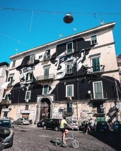 Un uomo che va in bicicletta davanti a un palazzo di Casa Elena - casa vacanze Napoli centro a Napoli