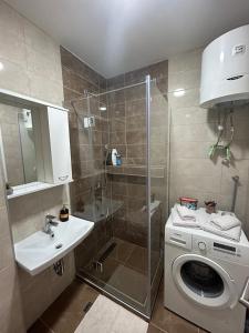 een badkamer met een douche en een wasmachine bij Apartman VUČKO in Pale