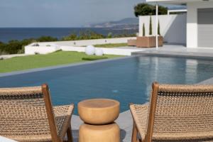 two chairs and a table next to a swimming pool at Nouvelle Villa in Ierápetra