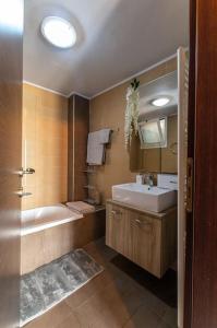a bathroom with a tub and a sink and a mirror at MegaLuxe Apartment in Heraklio Town