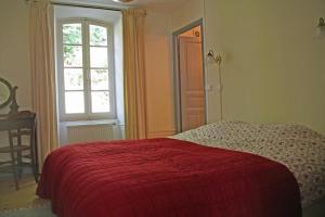 um quarto com uma cama vermelha e uma janela em Notre-Dame d'Escouloubre em Escouloubre