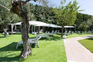 a group of white chairs and umbrellas in a park at Appia Antica Hotel in Corato