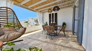 a porch with a swing and a table on a balcony at Plaka Philoxenia Apartments Milos in Plaka Milou