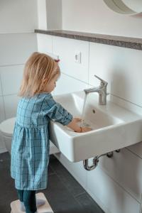 a little girl washing her hands in a sink at Ferienhaus am Mühlenweiher 2 in Leutkirch im Allgäu