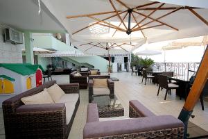 an outdoor patio with couches and tables and umbrellas at Montesan Luxury Apartment in Sveti Stefan