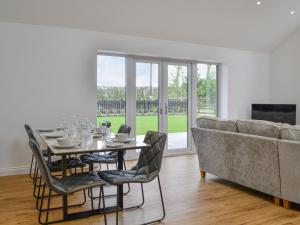 a dining room with a table and a couch at Old Byre Cottage - Uk43377 in Kirklinton