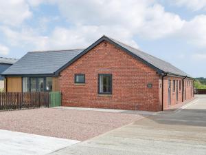 a red brick building with a black roof at Old Byre Cottage - Uk43377 in Kirklinton