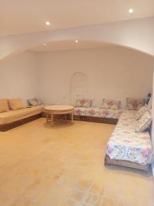 a living room with two beds and a table at Tamnsourt in Aït Ali