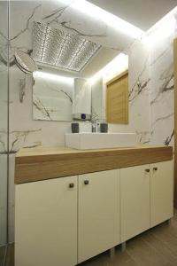 a white bathroom with a sink and a mirror at Apartman Giron in Zlatibor