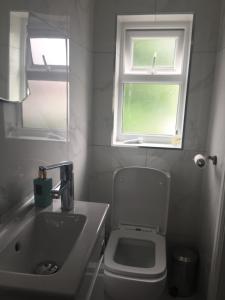 a bathroom with a toilet and a sink and two windows at home away from home in Croydon