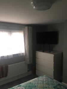 um quarto com uma cama e uma televisão numa cómoda em home away from home em Croydon