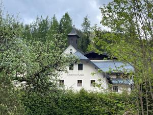 um edifício branco com uma torre em cima em Loft Krämerhaus Annaberg, Dachstein West em Annaberg im Lammertal