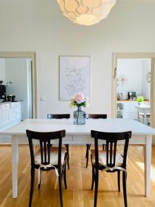 邁森的住宿－Ferienwohnung im Gästehaus，白色的餐桌,配有椅子和花瓶