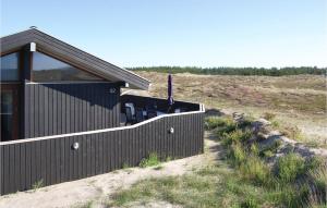 a building with a fence next to a field at Holiday Home Arvidvej Hvide Sande Denm in Bjerregård