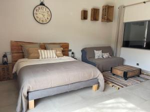 sypialnia z łóżkiem, kanapą i zegarem w obiekcie Logement atypique - Chevaux Miniatures Rhéa Horses w mieście Bargemon