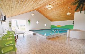 a pool in a room with green chairs at 5 Bedroom Stunning Home In ster Assels in Ljørslev