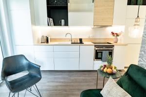 eine Küche mit weißen Schränken, einem Tisch und einem Stuhl in der Unterkunft Appartement Bocuse -terrasse -Oullins-Lyon in Oullins