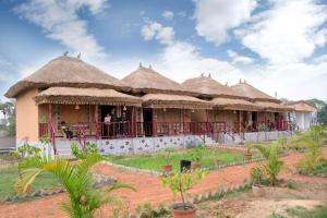 a building with thatched roofs with people on the balcony at Kopai View in Bolpur