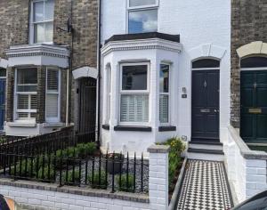 a white house with a black door and a fence at Stunning Victorian Terrace in the Golden Triangle in Norwich