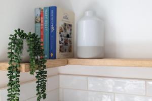 a shelf with books and a bottle of milk and a plant at Stunning Victorian Terrace in the Golden Triangle in Norwich