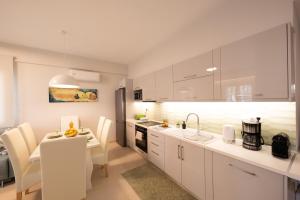 a kitchen with white cabinets and a dining table at Frises Corfu Town Apartment in Ágios Rókkos