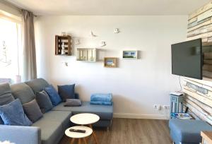 sala de estar con sofá azul y TV de pantalla plana en Ferienpark Sierksdorf App 302 - Strandlage en Sierksdorf