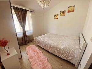 una camera con un letto bianco e un tappeto rosa di Mr&Mrs ApartHotel a Fălticeni