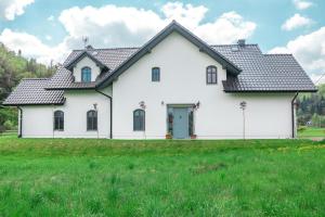 ein weißes Haus mit schwarzem Dach auf einem grünen Feld in der Unterkunft The Modern House in Raciechowice
