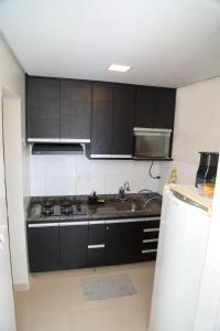 uma cozinha com armários pretos e um lavatório em AP 104-A Térreo Completo Aconchegante em Palmas