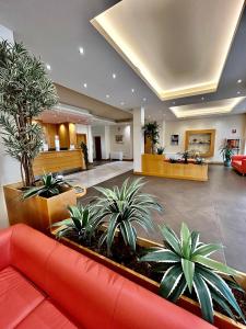 a lobby with a red couch and some plants at Hotel Ristorante Trendy in Prato