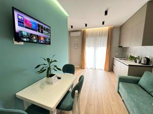 ein Wohnzimmer mit einem Tisch und einem TV an der Wand in der Unterkunft TreA Accomodations - Despacito TRB Sea View in Vlorë