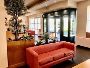 eine orangefarbene Couch in einer Lobby mit Pflanzen in der Unterkunft Hotel Ristorante Trendy in Prato