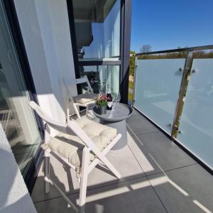 two white chairs and a table on a balcony at Apartament Marina Ostoya Pucka in Puck