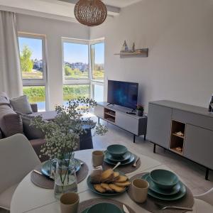 a living room with a table and a tv at Apartament Marina Ostoya Pucka in Puck