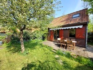 a house with a table and chairs in a yard at Chalet calme et cosy entre terre et mer in Berck-sur-Mer