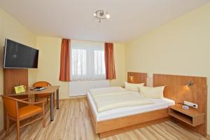 a bedroom with a bed and a desk and a tv at Hotel Reichskrone in Heidenau